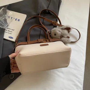 Dettaglio borsa in scamosciato a contrasto con finiture in pelle marrone e charm con coniglio