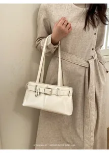 Detailansicht einer cremefarbenen Ledertasche mit Metallschnalle und Retro-Riemen-Design