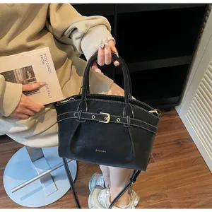 Detail of a black textured handbag featuring contrast white stitching and gold hardware