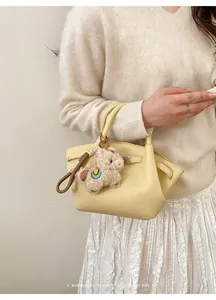 Detail der Crossbody-Tasche mit Lychee-Muster in Hellgelb und süßem Alpaka-Anhänger