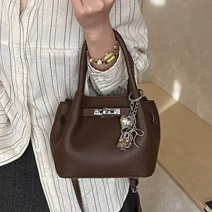 Braune Handtasche aus Leder mit Litschistruktur, silbernen Anhängern und Gurt