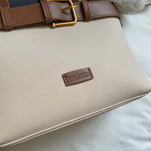 Dettaglio della borsa vintage in pelle scamosciata con fibbia dorata e logo in pelle