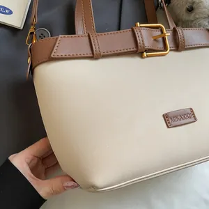 Dettaglio della borsa con trama beige e cinturino con fibbia in pelle marrone scuro