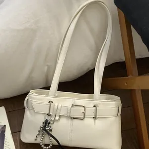 Minimalistische beige Baguette-Tasche mit Metallschnalle und Sternanhänger im Lifestyle-Stil