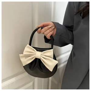 Dettaglio di un'elegante borsa in pelle nera con un grande fiocco color crema