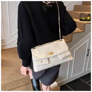 Detail of beige quilted leather tote with gold chain strap and metal twist lock