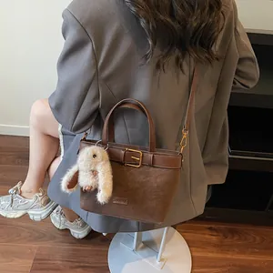 Dettaglio della borsa tote in pelle scamosciata marrone scuro con fibbia dorata e ciondolo a coniglio