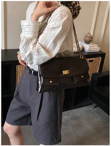 Detail of glossy quilted coffee leather shoulder bag with golden chain and clasp