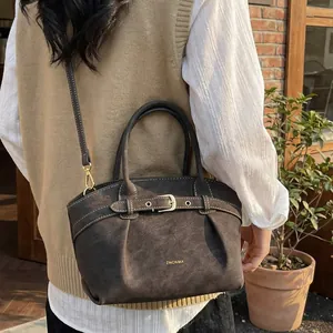 Dark brown matte leather handbag with pleated texture and adjustable strap shown on a model