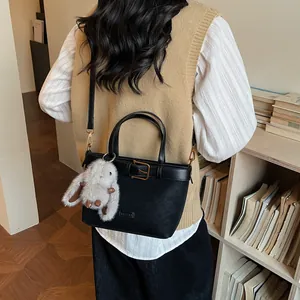 Dettaglio borsa vintage in pelle scamosciata nera con ciondolo a coniglio soffice
