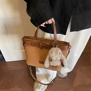 Dettaglio della borsa in finta pelle scamosciata marrone con fibbia e ciondolo a coniglio