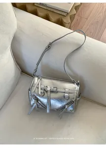 Detail of silver metallic cylinder bag featuring buckle strap and chic moto style aesthetic