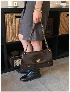 Detail showing high-capacity brown quilted leather shoulder bag with chain strap