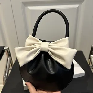 Elegante borsa a mano rotonda nera con grande fiocco color crema e manico superiore