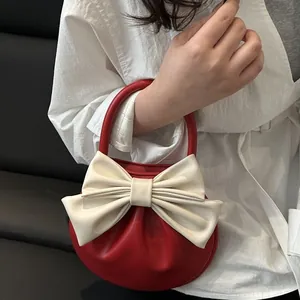 Elegante borsa a mano semicircolare rossa con grande fiocco crema e raffinata texture plissettata