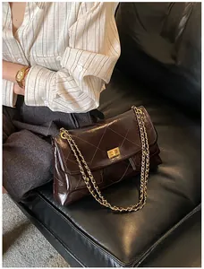 Detail of dark brown quilted leather texture and gold chain strap on shoulder bag