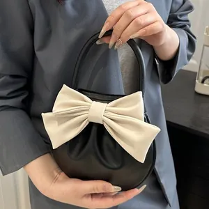 Elegante borsa rotonda nera con grande fiocco color crema e design in pelle pieghettata