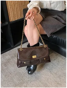 Detailed macro of a chocolate brown quilted leather bag with gold chain and clasp closure