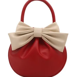 Elegante borsa a mano tonda rossa con grande fiocco color crema e manico superiore