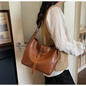 Detail of caramel brown leather tote bag showing vintage strap and buckle design