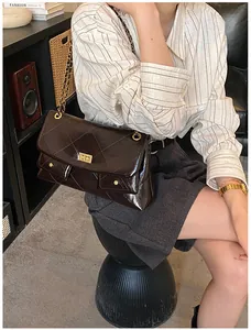 Close-up of brown quilted leather tote with gold metal buckle and chain strap