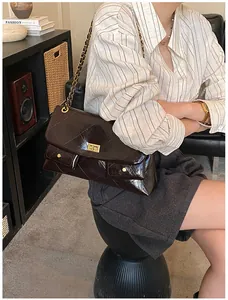 Detail of dark brown quilted tote bag featuring golden chain strap and vintage twist lock