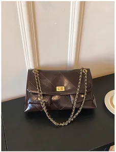 Detail of coffee diamond quilted oil wax leather bag with golden metal swivel lock
