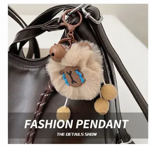Detail showing a plush bear charm with yellow pom-poms on a dark brown leather tote bag