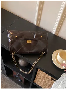 Detail of dark brown quilted leather tote with gold metal twist lock and chain strap