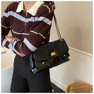 Detail of black quilted leather crossbody bag with gold-tone hardware and chain strap