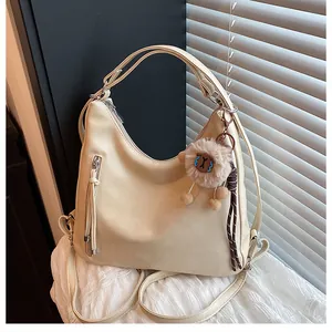 Detail view of cream hobo bag with sleek synthetic leather texture and cute sheep pendant