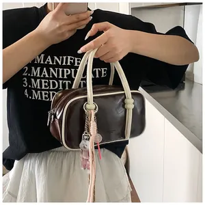 Détail du sac Boston vintage en cuir marron avec passepoil blanc et breloque chien
