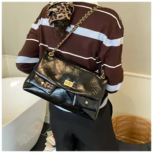 Detail of black quilted chain bag featuring dual front pockets and a vintage gold turn-lock