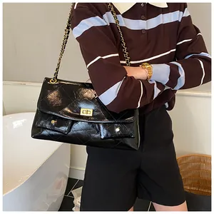 Detail of black quilted chain strap bag with golden clasp in a chic lifestyle setting