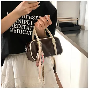 Détail d'un sac Boston en cuir marron avec bordure crème et pendentif ours mignon