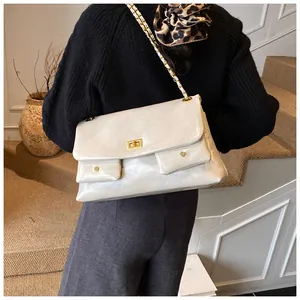 Quilted beige shoulder bag with gold chain strap shown on model in a modern interior
