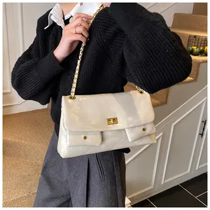 Close-up of white quilted tote bag with golden twist lock and metal chain strap