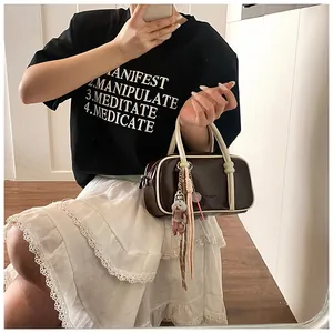 Détail du sac Boston avec bordure en cuir contrasté et breloque chiot mignonne