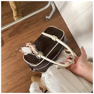 Gros plan d'un sac Boston rétro marron avec pompon et détails de bordure blancs