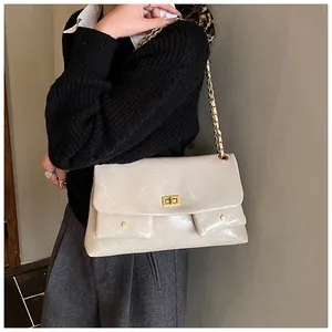 Close-up of beige quilted tote bag featuring gold chain strap and dual front pockets