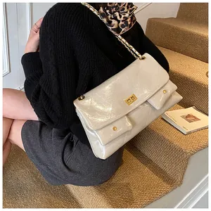 Close-up of cream quilted patent leather tote bag with gold chain strap and dual front pockets