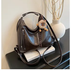 Detail view of dark brown faux leather tote with adjustable straps and plush charm