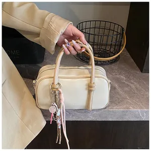 Vue détaillée du sac Boston crème avec pompons décoratifs et cuir synthétique lisse
