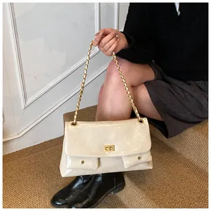 Macro detail of beige quilted patent leather bag with gold twist lock and chain strap