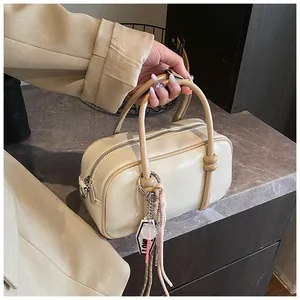 Vue de dessus du sac Boston crème avec texture cuir et breloque chaîne en métal