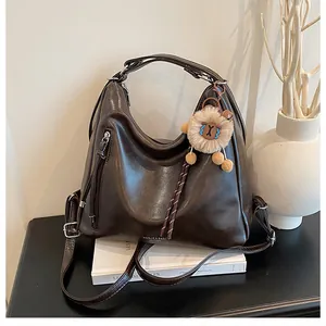 Deep brown leather tote bag with vertical zipper pocket and lion plush charm decoration