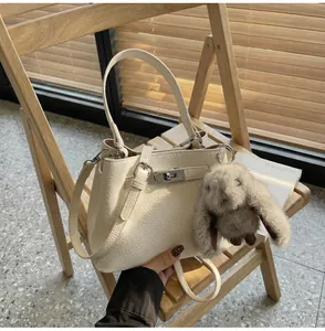 Detail of cream pebbled leather bucket bag with silver clasp and plush bunny charm