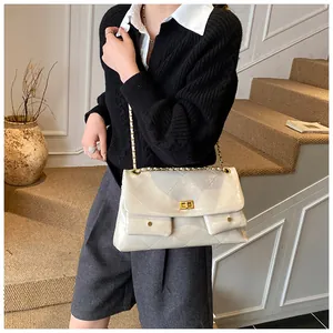 Detail of cream quilted tote bag featuring golden chain straps and double front pockets