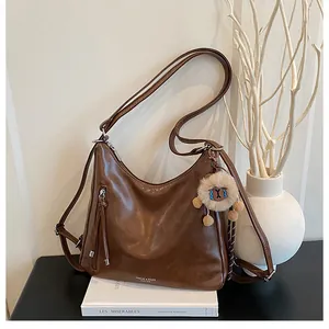 Detail view of a vintage dark brown hobo bag with a plush charm on a book