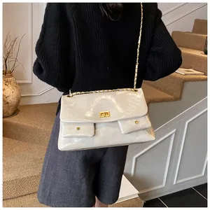 Close-up of beige quilted tote bag with gold chain strap and dual front pocket details